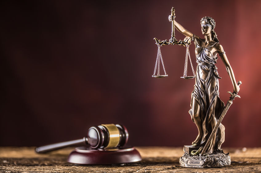 Woman justice statue holding balanced scales next to gavel